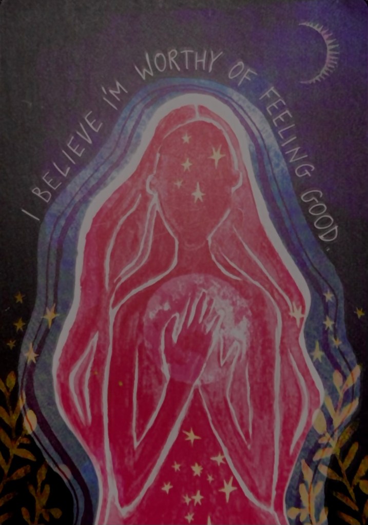 This shows an illustration of a painted, pink woman holding the moon. Around her are the stars and the words "I believe I'm worthy of feeling good."